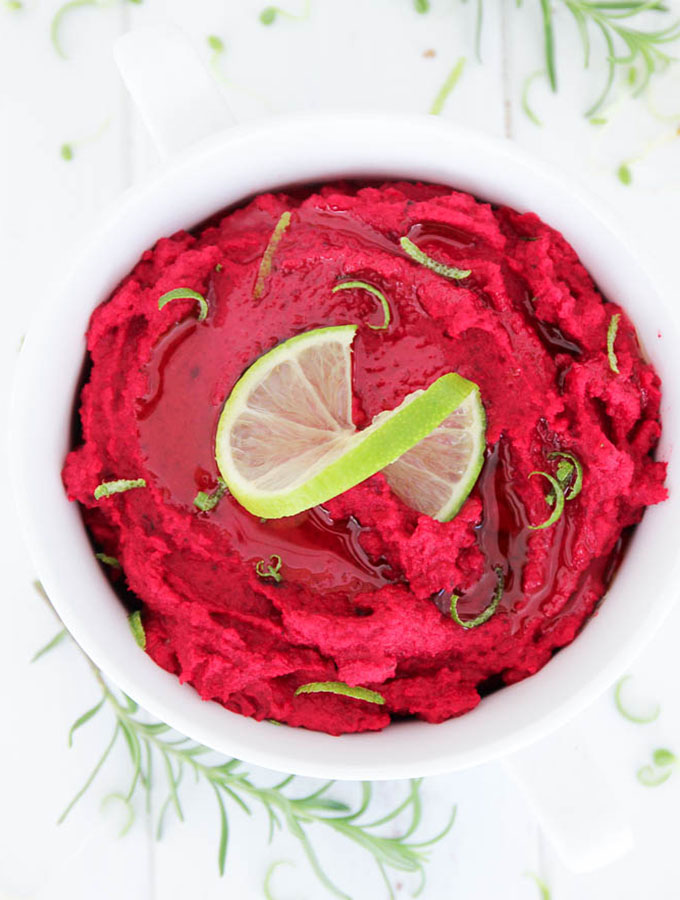 overhead view of a bowl of beet hummus with a lime slice on top