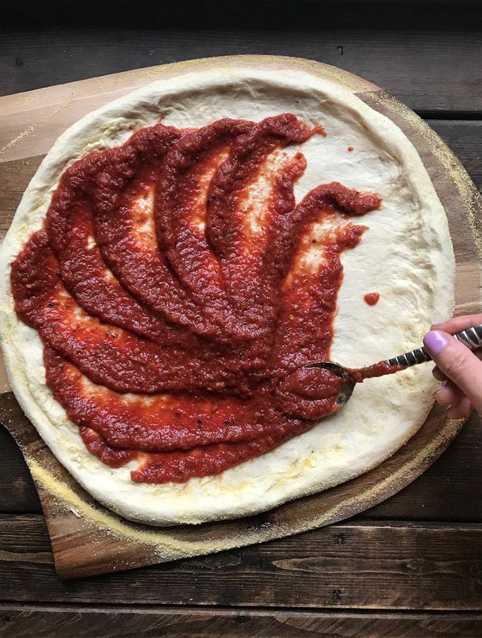 spreading sauce on a pizza dough