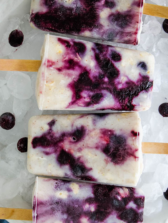 blueberry yogurt popsicles plated on a bowl of ice.