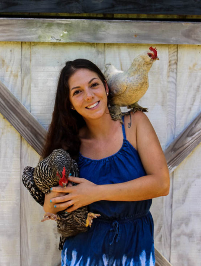 sherry brubaker with chickens posed infront of her barn