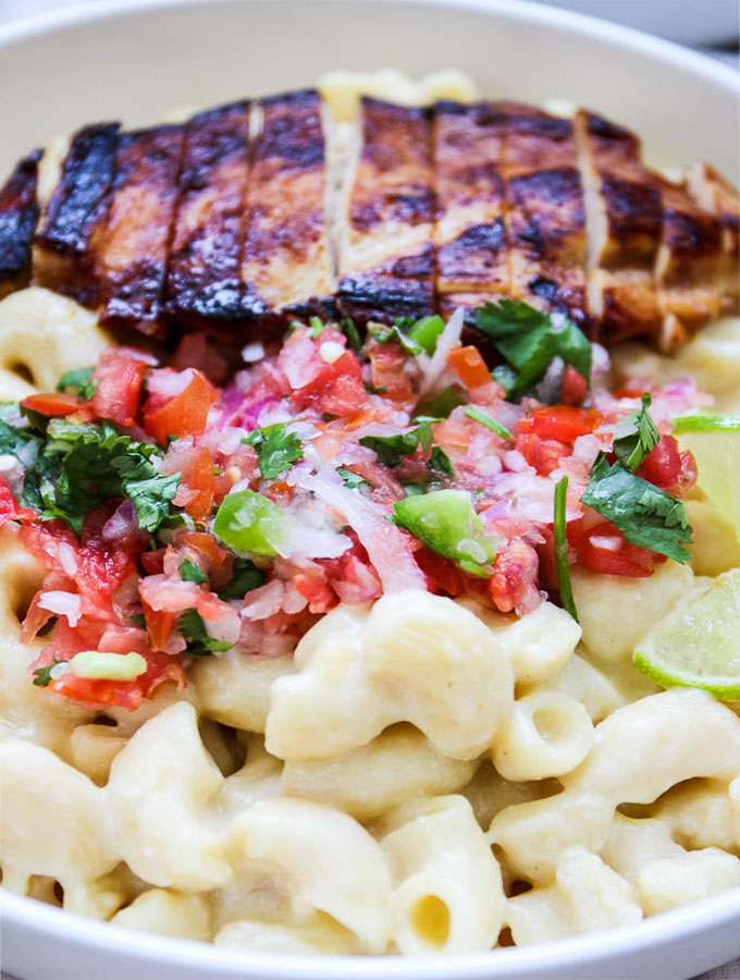 close up shot of creamy and cheese mac and cheese with seared garlic lime chicken