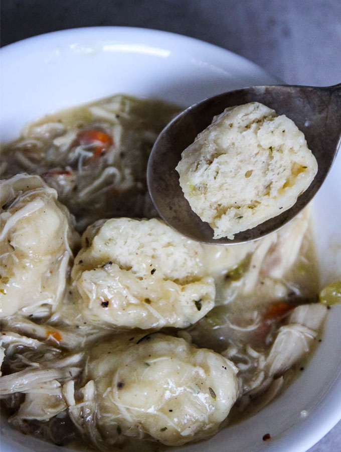 chicken and dumplings has fluffy and airy dumplings shown halved on a spoon.