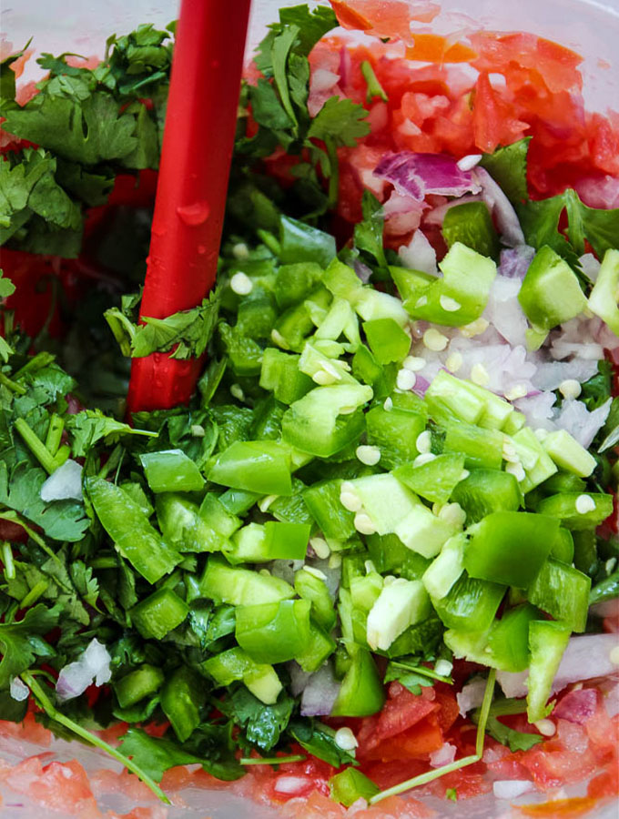 Pico de gallo is diced finely and combined in a bowl to serve.