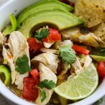Mexican chicken and lime soup close up to show shredded chicken, bites of pepper, and the fixings like avocado slices and chips.