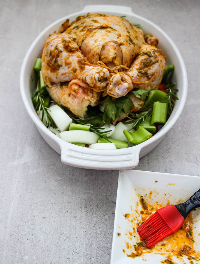 herb and wine roasted whole chicken is prepared by using a culinary brush to coat the chicken with a butter and wine based marinade.