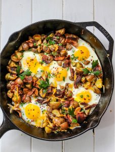 Cheesy egg, bacon, and potato skillet is made easily in a cast iron pan under thirty minutes.