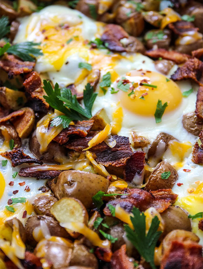 Bacon, egg, and potato cheesy skillet is served up with easy over eggs and crispy bacon.