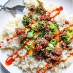 Easy 30 minute meal korean beef and broccoli rice bowl is topped with siracha sauce and sesame seeds.