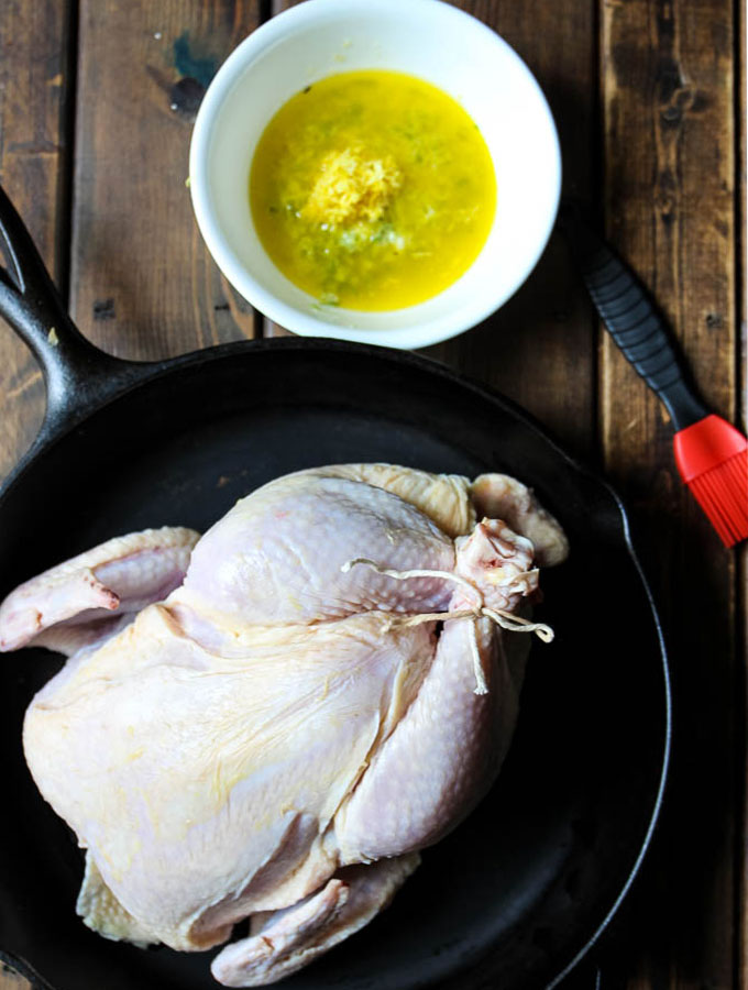 Lemon and herb chicken whole roasted in the oven is prepared by combining the butter with garlic, herbs, lemon juice, and salt, then slathering it on the chicken under the skin.