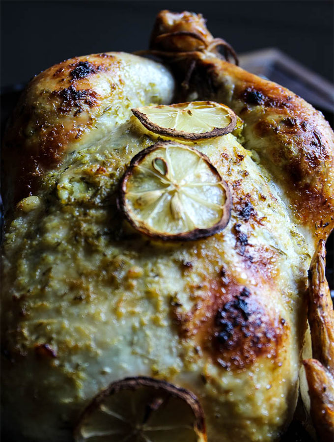 herb and lemon chicken is fresh out of the oven and roasted to browned perfection with lemon slices and juicy thighs.