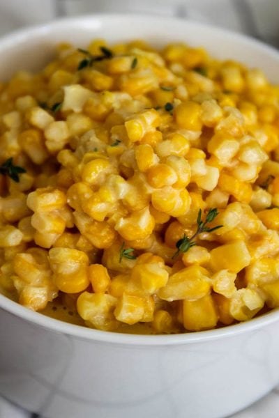 Creamed corn with parmesan is topped with fresh thyme to add color, texture, and flavor.