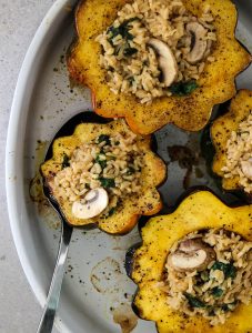 Vegetarian stuffed squash is halved and stuffed with a rice filling and place in a baking dish.