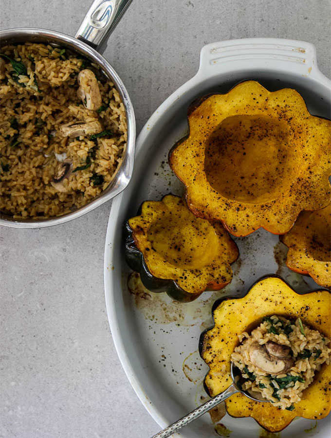 Acorn squash is in the process of being stuffed with a savory herb rice.