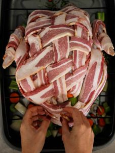 bacon wrapped turkey begins with wearing bacon on top of the turkey before cooking.