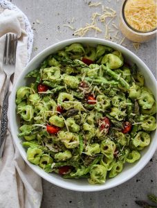 Green Goddess Tortellini Salad is plated with parmesan cheese and forks.