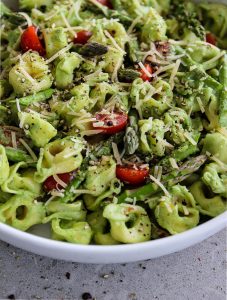 Green Goddess Tortellini Salad is mixed together and topped with parmesan cheese and plated in a white bowl.