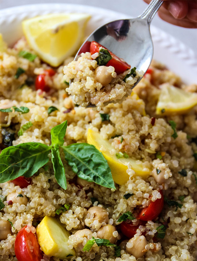 Quinoa salad is plated in a white bowl with a spoon to show texture and colors.