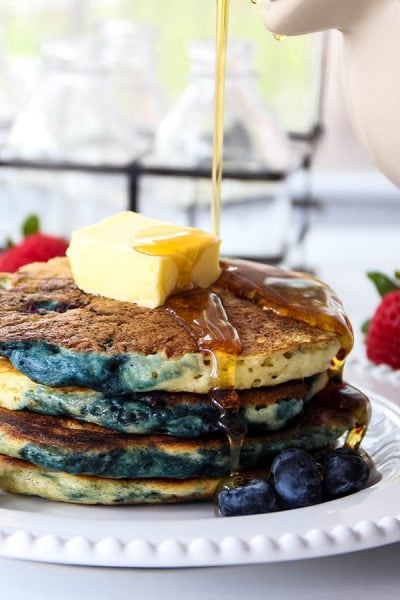 Buttermilk pancakes are stacked and topped with butter and maple syup.