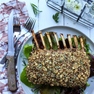 Pecan crusted rack of lamb is cooked and displayed on a white plate.