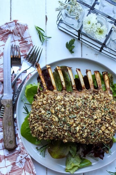 Pecan crusted rack of lamb is cooked and displayed on a white plate.