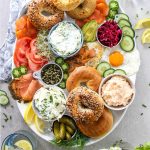 Lox and bagels breakfast board is displayed on a white platter.
