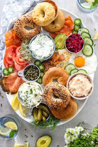 Lox and bagels breakfast board is displayed on a white platter.