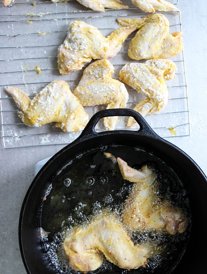Lemon pepper chicken wings are deep fried in a dutch oven.