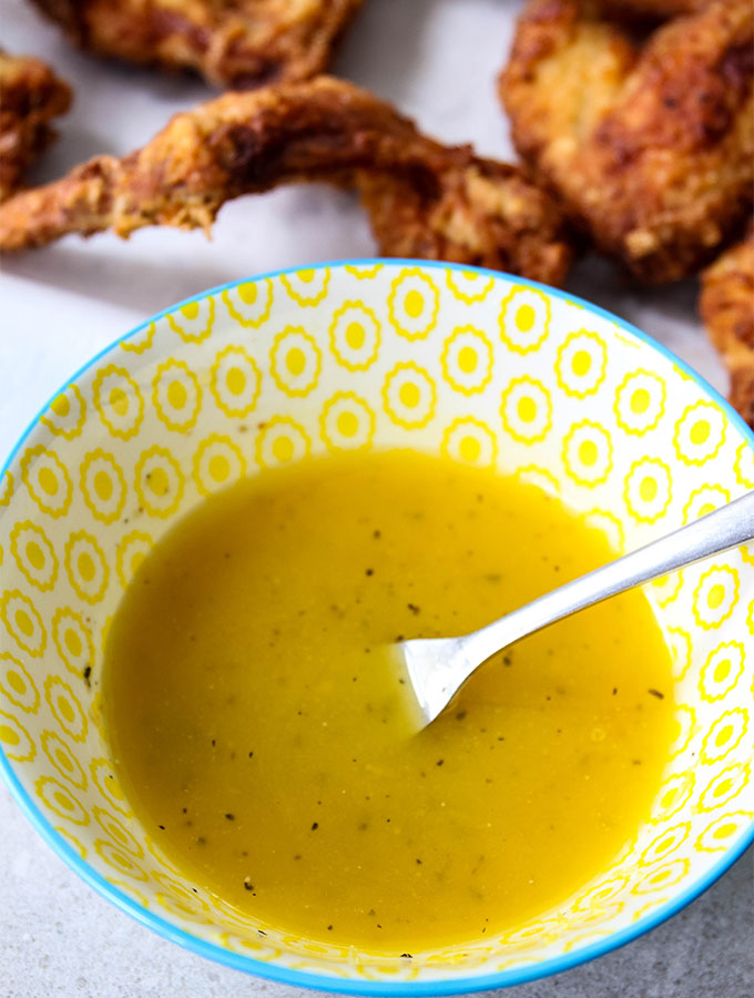 A lemon pepper sauce is mixed in a yellow bowl.