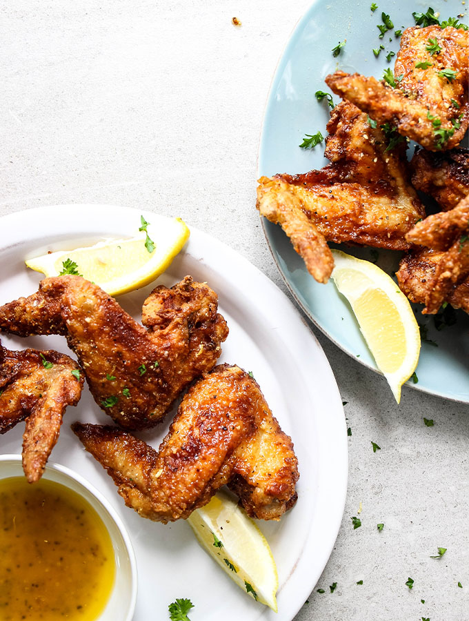 chicken wings on a plate with lemon wedges