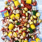 A low country boil is tossed on a newspaper and served with melted butter.