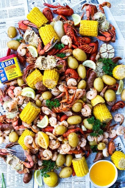 A low country boil is tossed on a newspaper and served with melted butter.