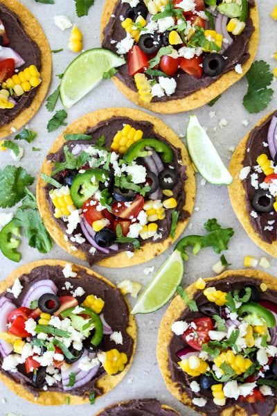 Vegetarian tostadas are topped with all the fixings and wedges of lime.