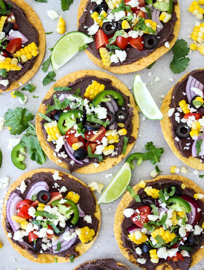 Vegetarian tostadas are topped with all the fixings and wedges of lime.
