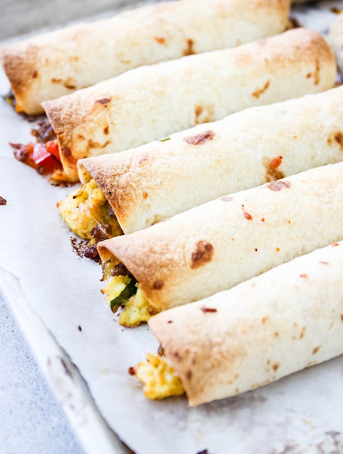Baked breakfast taquitos are stuffed with eggs, sausage, cheese, and bell peppers.