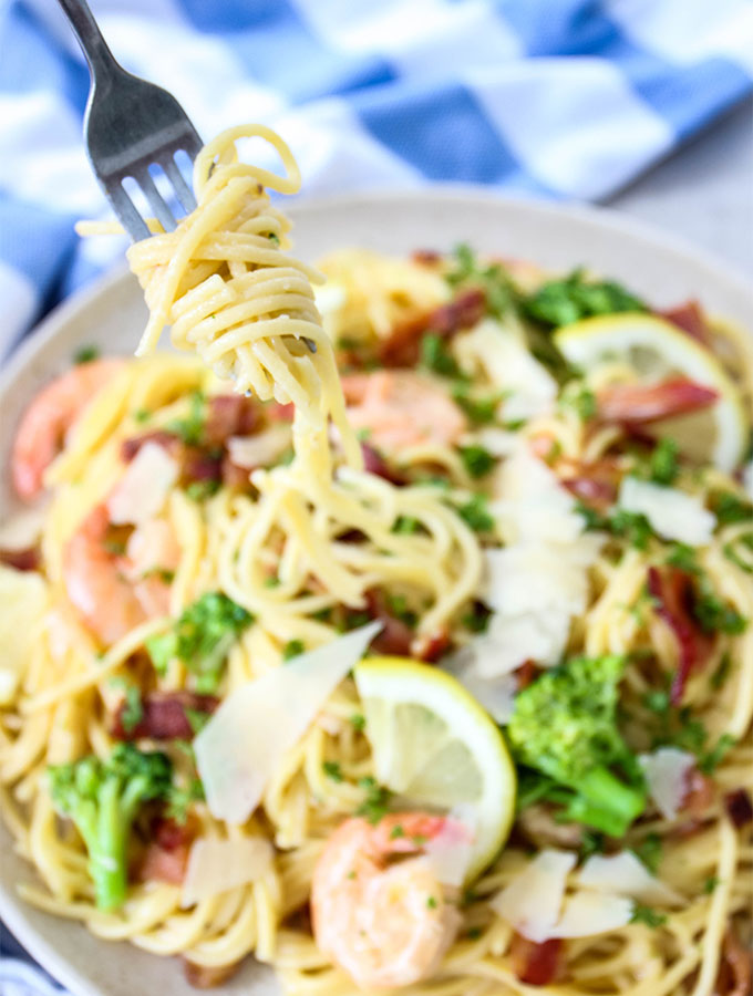 Creamy Bacon and Shrimp Scampi is twirled on a fork for a closeup shot.