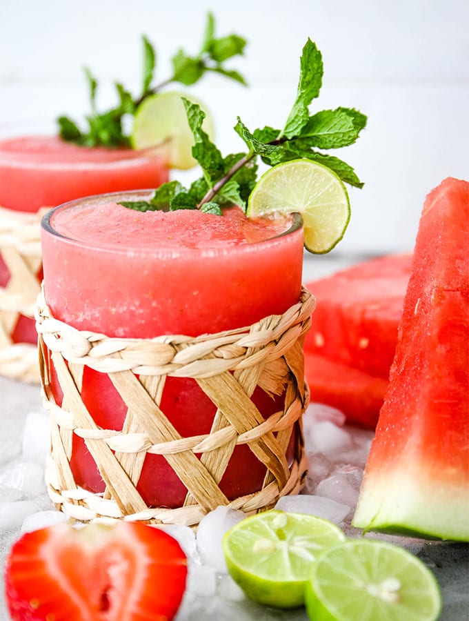 Frozen Strawberry Watermelon Margaritas are poured into small decorative glasses and plated with more fresh watermelon.