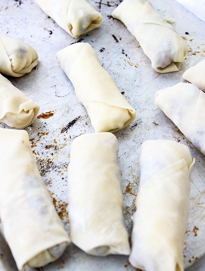 Philly Cheese Steak Egg Rolls are rolled tight and placed on a baking tray before being fried.