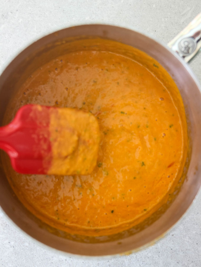 Tomato bisque is blended with an blender then added back to the pot.
