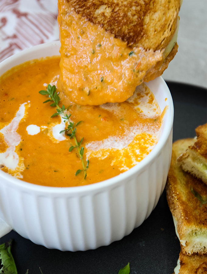 A grilled cheese with pesto is dunked in a creamy tomato bisque.