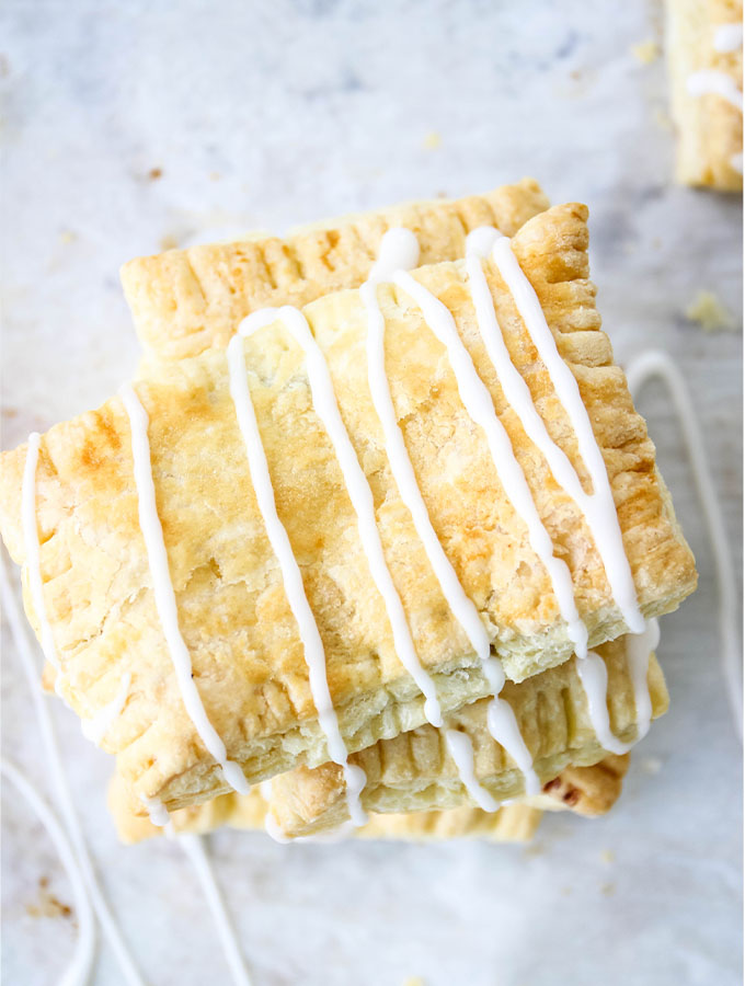 Homemade toaster strudels are stacked and topped with icing.