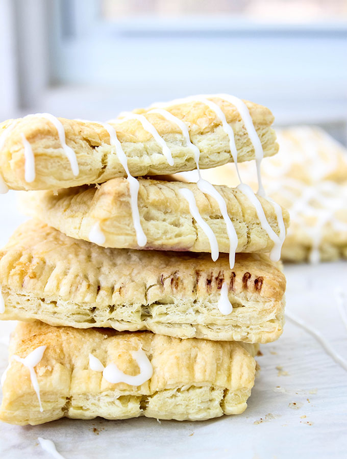 Homemade toaster strudels are stacked and topped with gooey icing.