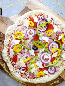 Italian Sub Pizza is topped with all the ingredients and is about to be baked.