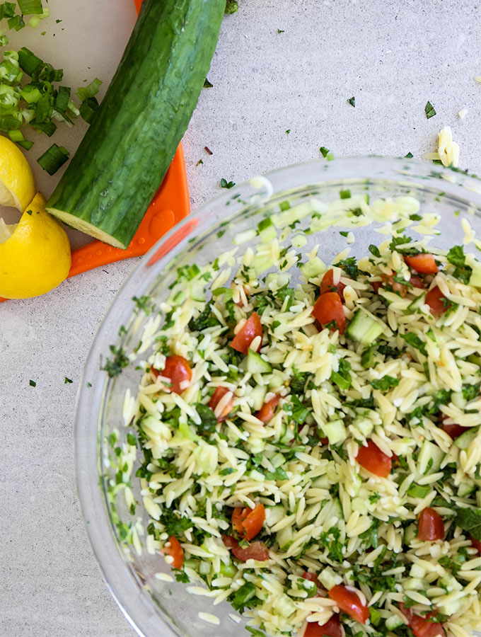 Summer Tabouli Orzo Pasta Salad is tossed in glass serving bowl.