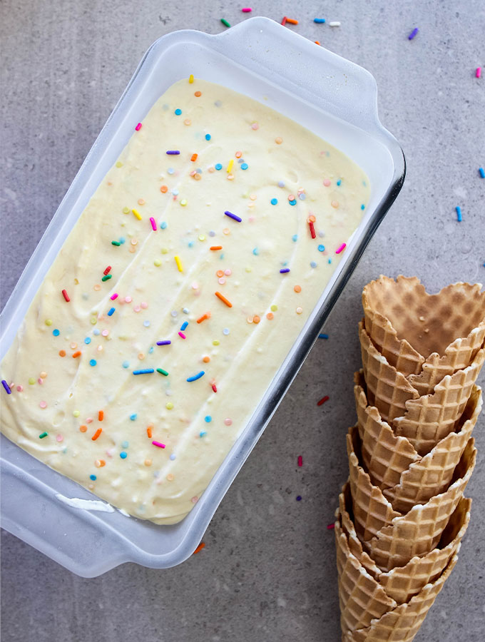 No Churn Cake Batter Ice Cream is taken out of the freezer and placed next to waffle cones.
