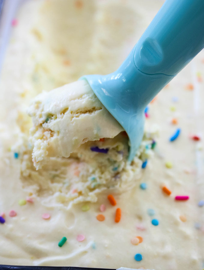 No Churn Cake Batter Ice Cream is scooped with a blue ice cream scooper.