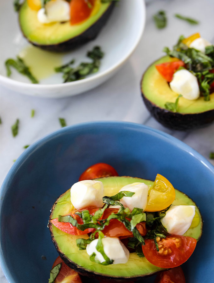 5 Minute Caprese Stuffed Avocados is plated and topped with more basil.