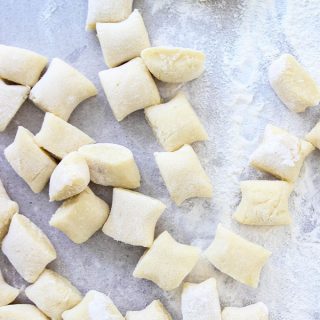 Homemade Italian Gnocchi is cut into pieces on a floured surface.