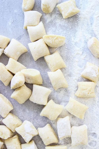 Homemade Italian Gnocchi is cut into pieces on a floured surface.