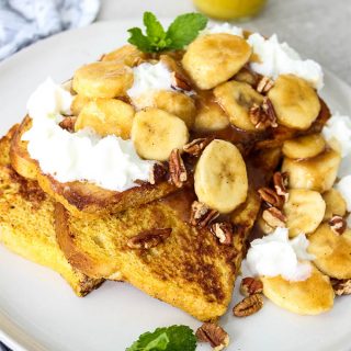 Banana Foster French Toast is plated and served with a glass of orange juice.