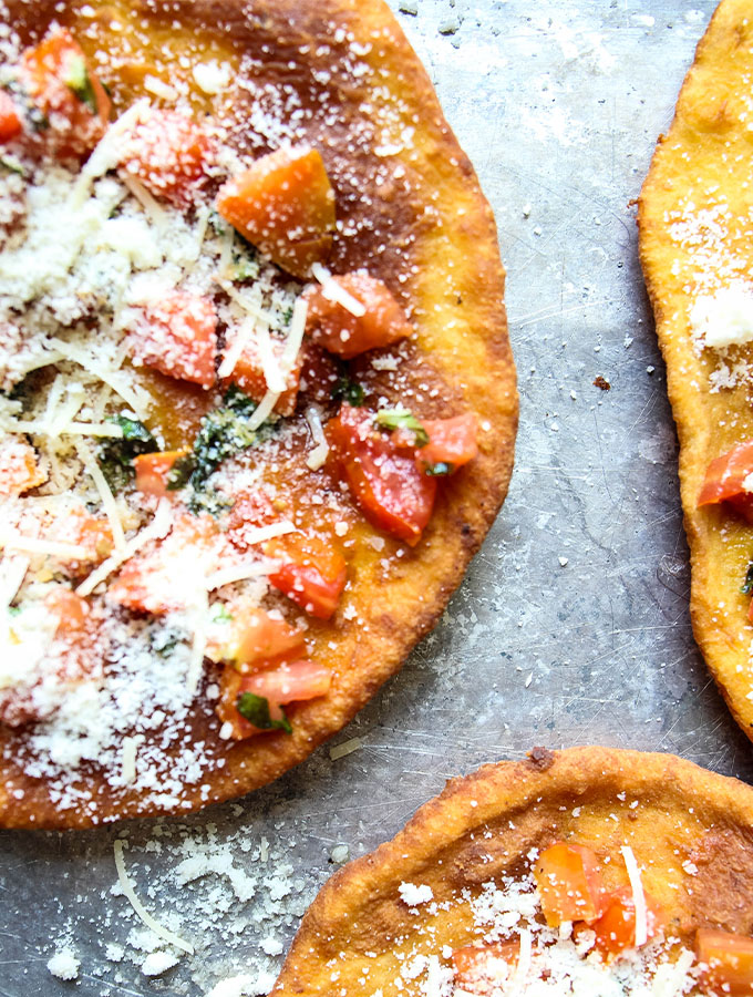 Deep Fried Neapolitan Pizza is baked on a baking sheet with tomatoes, basil, and cheese.